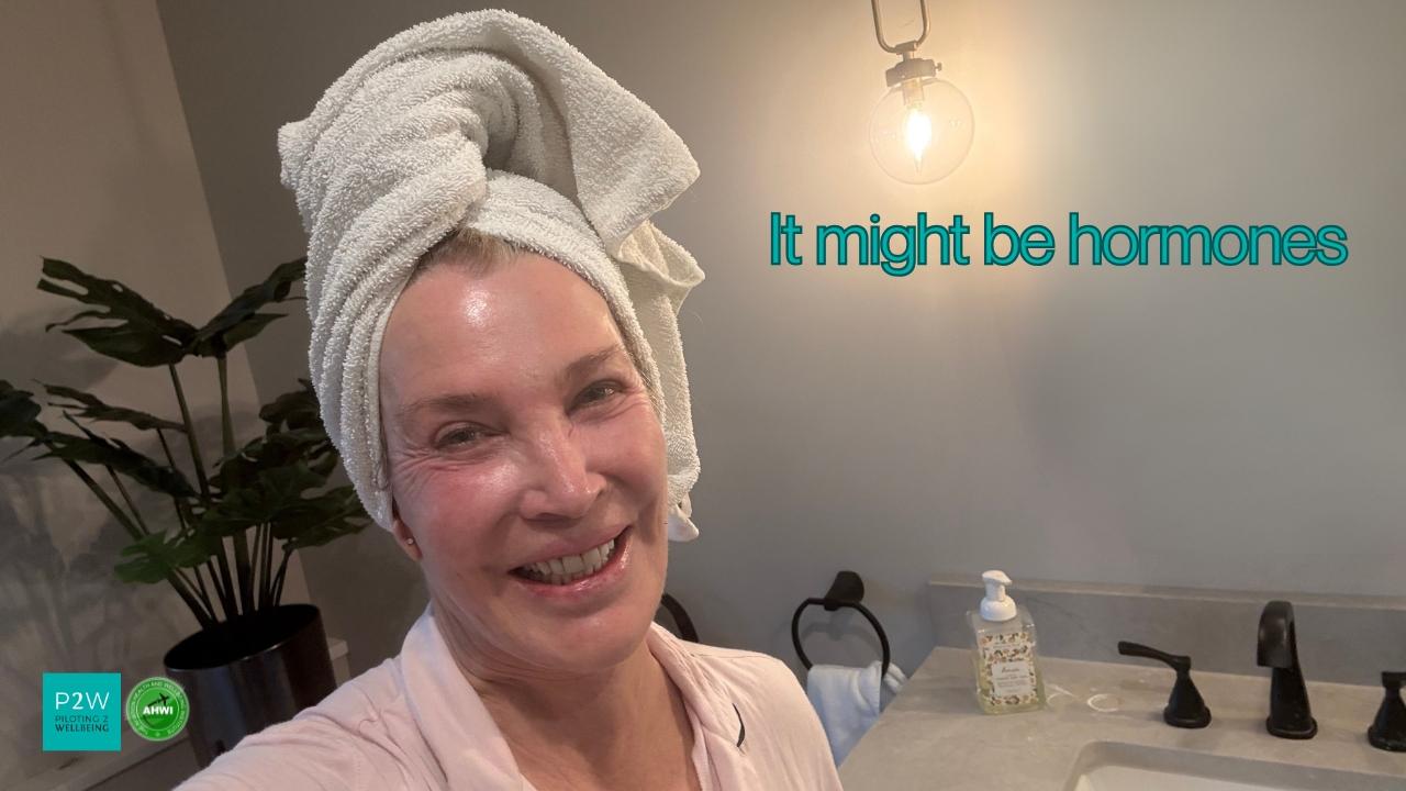 A woman with a towel wrapped around her head smiles in a bathroom; text on the image reads "It might be hormones.